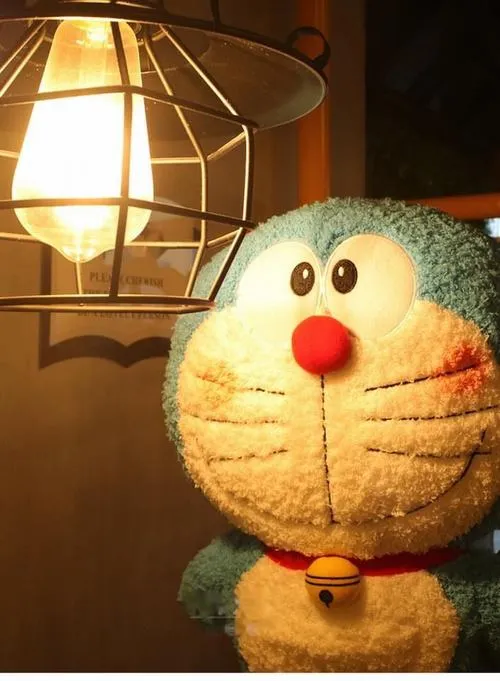 Mô hình Doraemon bằng len được khâu vá tỉ mỉ ngồi im lặng dưới ánh đèn vàng của chiếc đèn học mang lại cảm giác hoài niệm thật êm đềm.
