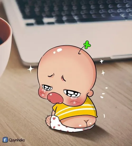 Em bé chibi đầu tròn ngồi trên bàn gỗ cạnh bàn phím, miệng chu ra thẫn thờ như đang lạc mood giữa bối cảnh đời thường