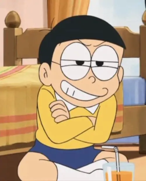 Nobita khoanh tay ngồi trên giường, đôi mắt liếc xéo sau kính và áo vàng cay cú gợi vibe bị chọc tức nhưng vẫn cố giữ mặt