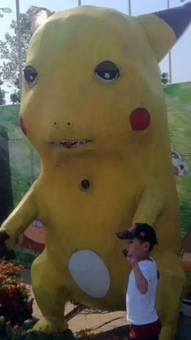 Mascot Pikachu khổng lồ đứng ngoài trời cạnh người thật, thân vàng mềm và khuôn mặt méo nhẹ nhìn vừa kỳ vừa vui