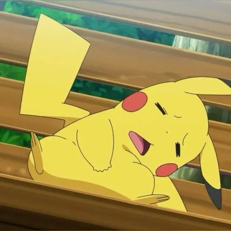 Pikachu nằm dài trên mặt sàn gỗ, mắt nhắm lim dim và má hồng mềm tạo cảm giác buồn ngủ rất dễ thương