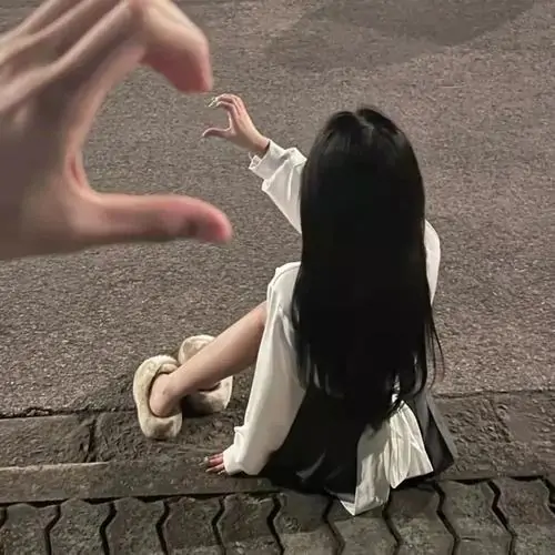Bàn tay tạo hình trái tim hướng về cô gái ngồi xa trên vỉa hè, tông nâu xám đời thường hợp ảnh hồ sơ cá nhân cho nữ