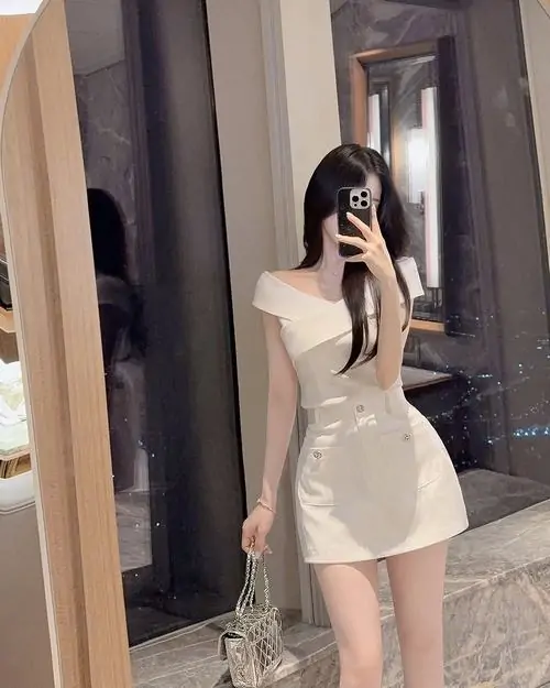 Gương đứng trong phòng làm ảnh phái đẹp diện đồ khoe dáng rõ hơn, cô gái váy trắng che mặt, một tay đặt nhẹ lên tóc