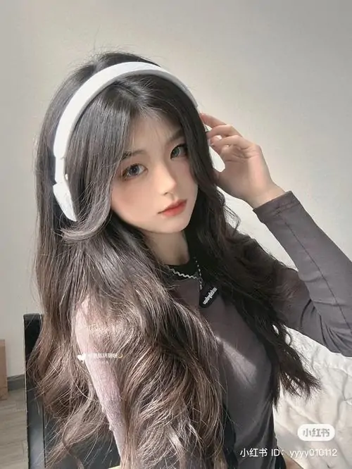 Khăn trắng ôm nhẹ khuôn mặt nhỏ, cô gái chu môi đáng yêu, tóc mái rơi tự nhiên và biểu cảm tinh nghịch trong phòng