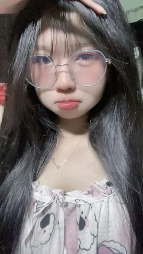 Tông ảnh trắng đen làm nổi mái tóc dài và kính gọng đen, cô gái cúi mắt bên áo trắng tạo khoảnh khắc yên tĩnh