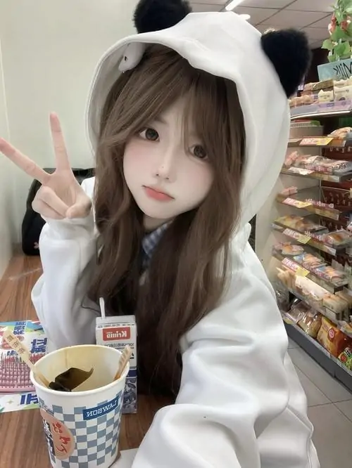 Bàn cà phê đêm với ánh tím hồng làm nền, cô gái tóc dài mặc áo tối màu, cầm ly và nhìn máy ảnh nhẹ nhàng