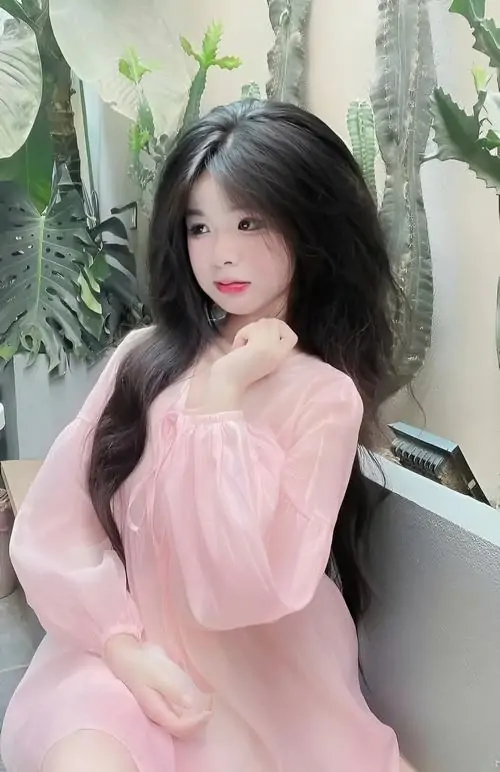 Cô gái nằm nghiêng trên gối, váy hoa nhí sáng màu, kẹp tóc bướm trắng và đôi mắt lim dim tạo nét mềm mại