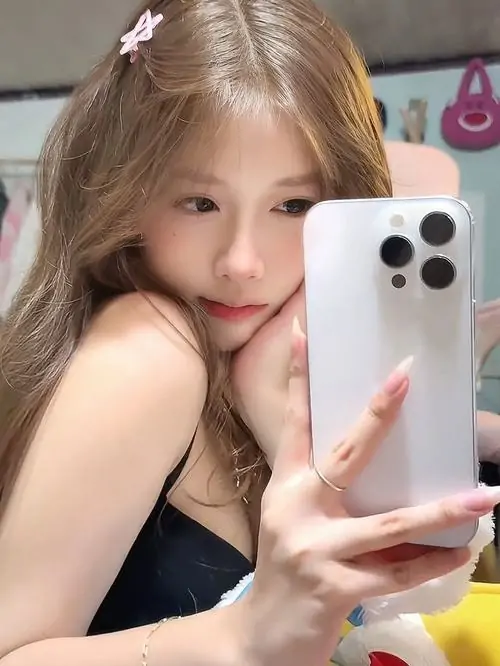 Gái xinh cute trùm mũ lông xám, khuôn mặt nhỏ lấp ló dưới phần mũ mềm và đôi mắt nhìn máy ảnh đầy đáng yêu