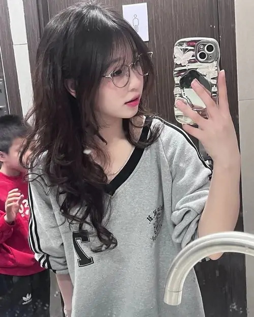 Tán cây xanh phủ quanh lối đi, cô gái mặc áo rộng màu trắng, đội mũ mềm và che nắng bằng dáng đứng tự nhiên