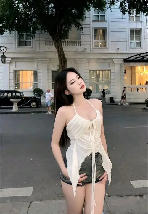 Trên phố chiều sáng nhẹ, ảnh thiếu nữ dáng chuẩn diện váy trắng ngắn, mái tóc đen thả tự nhiên và dáng đứng tự tin