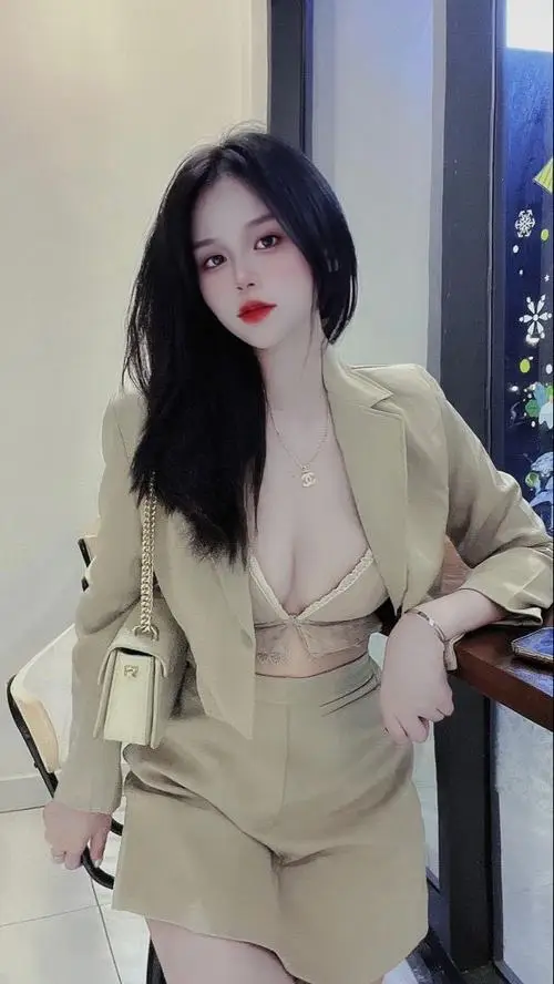 Bộ vest be giúp hình hot girl vóc dáng đẹp thêm hiện đại, cô gái đứng thẳng với mái tóc đen dài và môi đỏ nổi bật