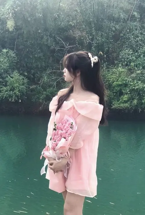 Bờ hồ xanh yên tĩnh làm nổi bật hình gái đẹp mặc váy hồng, cô gái quay lưng ôm bó hoa với dáng vẻ dịu dàng