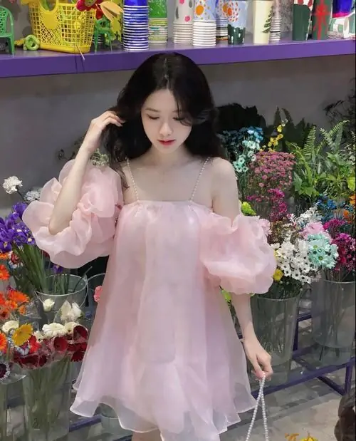 Khu vườn nhiều hoa làm nền cho ảnh hot girl đồ pinky, váy tay bồng màu hồng nhạt và mái tóc đen thả nhẹ
