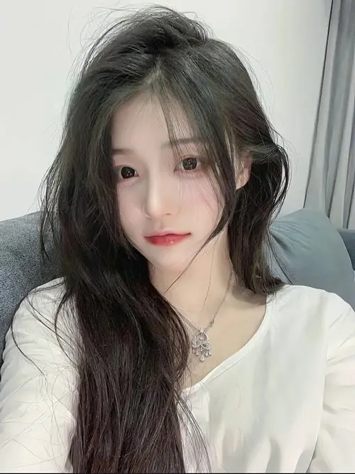 Áo len trắng mềm làm nổi bật làn da sáng, cô gái tóc đen dài nhìn thẳng với gương mặt thanh tú và nét duyên nhẹ nhàng