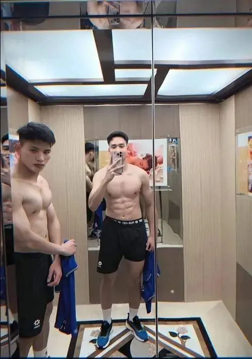 Trước gương phòng gym, hai chàng trai tạo dáng sau buổi tập, mặc quần thể thao, thân hình săn chắc và không khí rất đời thường