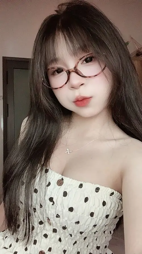 Ánh đèn phòng ngủ dịu nhẹ phủ lên cô gái mặc váy ngủ trắng, mái tóc rối nhẹ và biểu cảm ngái ngủ rất đáng yêu