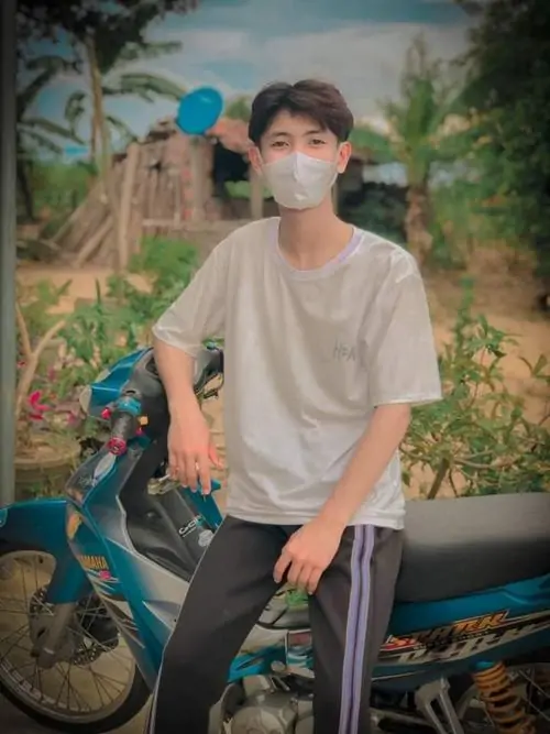 Khẩu trang trắng che nửa mặt khiến cậu bạn K13 mặc áo be ngồi trên xe máy trông kín đáo, dáng ngồi bình thản