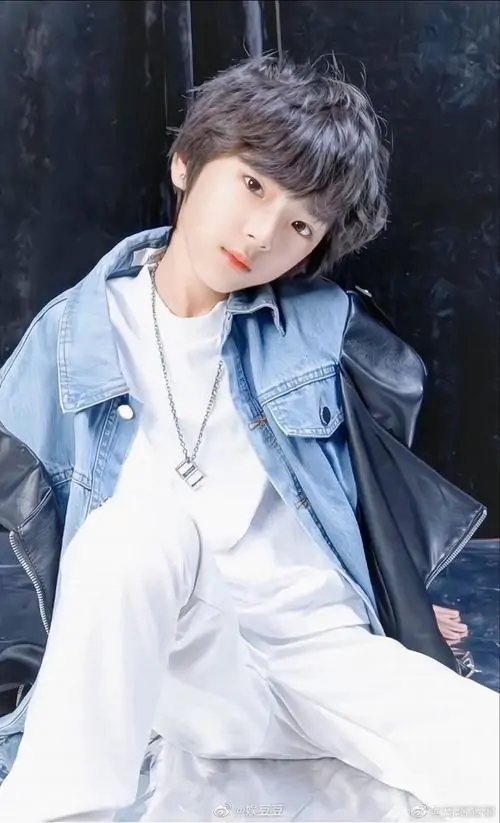 Lớp áo denim phủ ngoài sơ mi trắng giúp bạn nam tóc xám nâu nổi bật, ánh nhìn nghiêng và nền tối tạo cảm giác hơi lạnh
