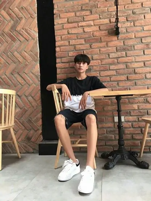 Ảnh trai đẹp 2k8 mặc áo đen ngồi ở quán gạch đỏ, dáng thư thái cùng đôi giày trắng tạo cảm giác đời thường