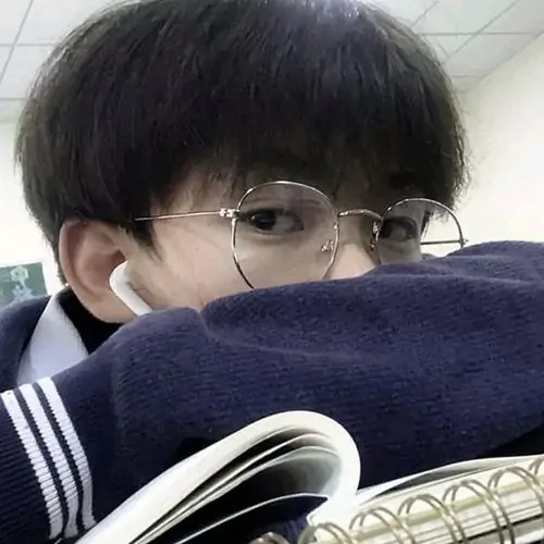 Cậu bé đeo kính đang che miệng bằng khăn trong tư thế dễ thương.