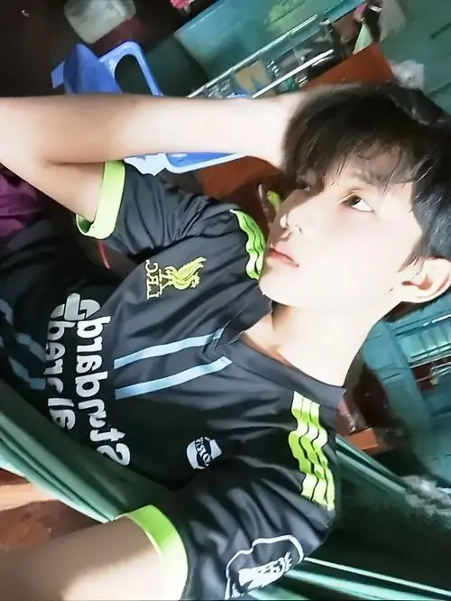 Cậu nhóc trong bộ đồ thể thao đen đang nghiêng đầu nhìn lên với vẻ tinh nghịch dễ thương.
