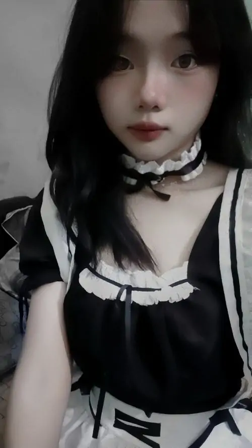 Gương mặt trắng sáng nổi bật trong khung hình gần, cô gái mặc cổ áo nơ đen và váy hầu gái viền trắng rất nhẹ nhàng