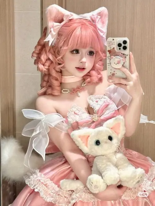 Nàng tóc hồng tạo dáng selfie trước gương, váy trắng hồng cùng gấu bông nhỏ khiến tổng thể mềm mại và đáng yêu