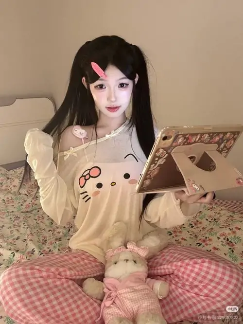 Trên giường phòng ngủ, gái xinh mặc pinky ôm gấu bông với gương mặt trắng sáng, tóc đen dài và ánh nhìn nhẹ nhàng