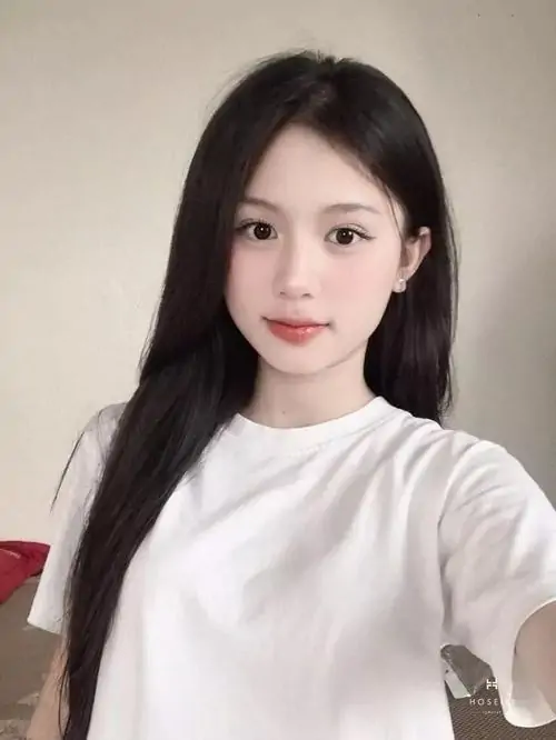 Nền tường sáng làm ảnh tuyệt sắc giai nhân thêm gọn mắt, cô gái mặc áo cổ lọ trắng nhìn thẳng với nét mặt dịu dàng