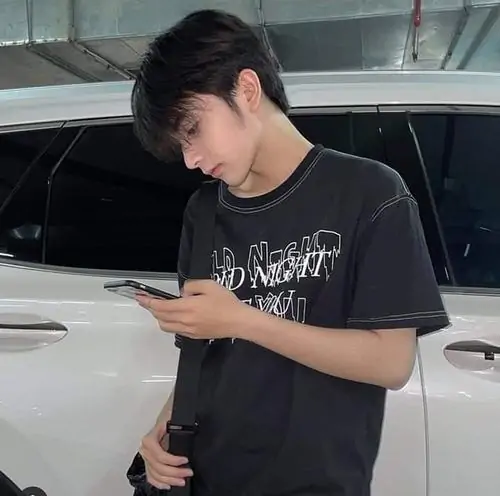 Ánh đèn quán nước hắt vàng lên gương mặt cậu bạn áo đen, tay chống cằm và biểu cảm yên yên khá dễ nhìn