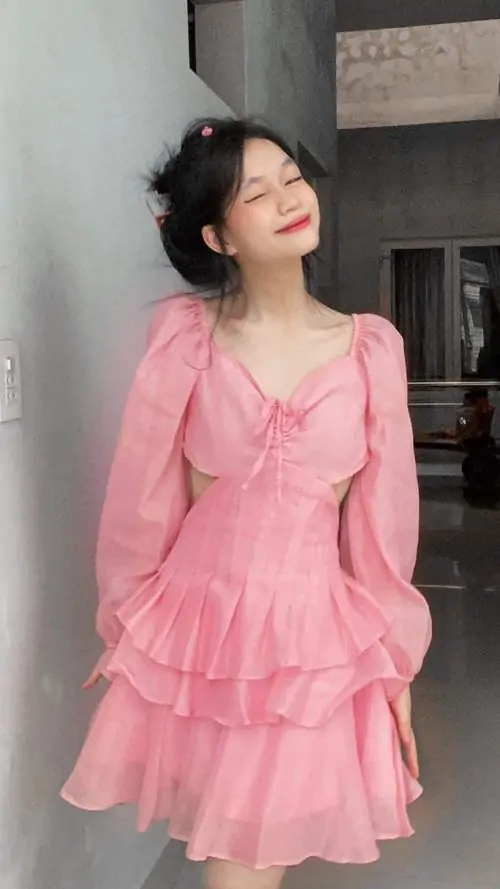 Bộ váy hồng hai dây nhiều tầng làm nổi bật vóc dáng người mẫu, mái tóc đen búi cao và dáng đứng thanh thoát