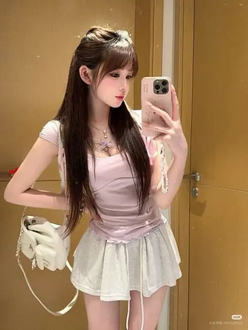 Gái xinh mặc pinky đứng dưới nắng hoàng hôn, tà váy xòe bay nhẹ và gương mặt nghiêng tạo nét lãng mạn