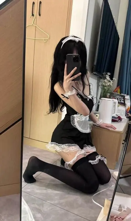 Phong cách Akihabara hiện rõ qua váy đen trắng, tất ngang đùi và phụ kiện tóc đáng yêu khi người mẫu tạo dáng trước bảng hiệu
