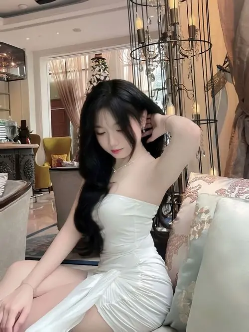 Trong căn phòng ấm sáng, hình nền cô gái mặc váy trắng ngắn ghi lại dáng ngồi cúi đầu với mái tóc đen dài