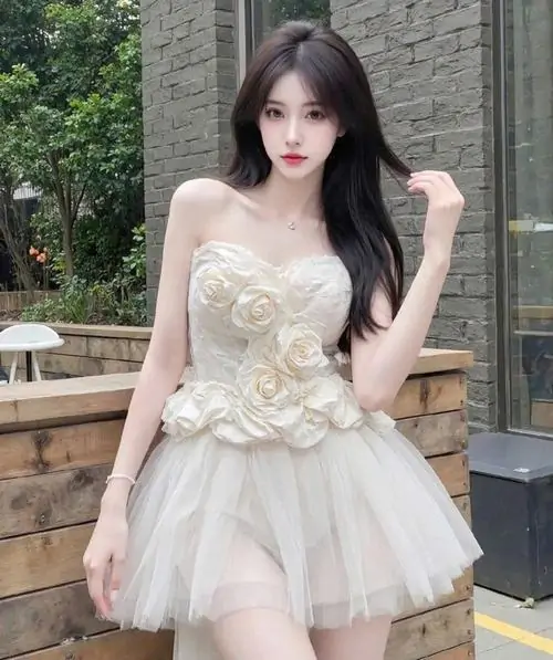 Bên khung cửa sổ lớn, cô gái váy trắng cổ vuông đứng nghiêng, mái tóc xoăn nhẹ và vòng cổ nhỏ tạo điểm nhấn