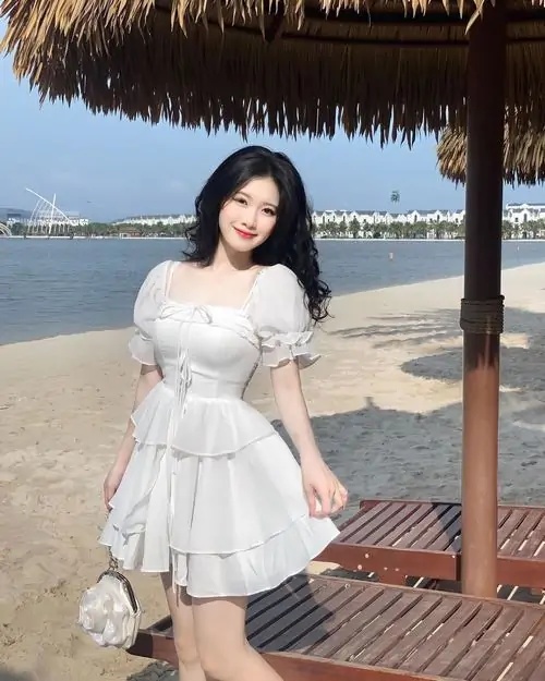 Nền cỏ xanh ngoài trời làm bộ váy trắng ngắn thêm sáng, cô nàng cúi nhìn bó hoa với vẻ mặt rất hiền