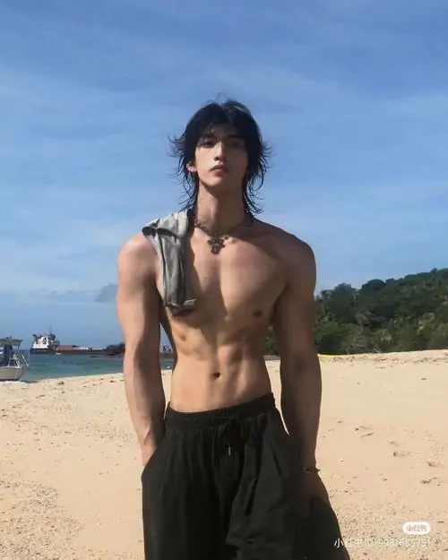 Bên hồ bơi buổi tối, chàng trai ngồi thả lỏng với vòng cổ mảnh, da rám nắng và thân trên chắc khỏe
