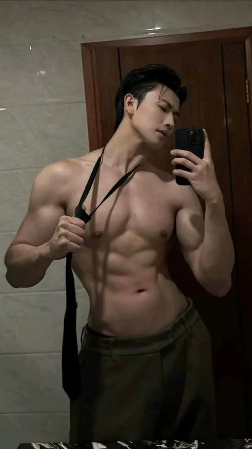 Ánh sáng studio chiếu xiên lên cơ ngực chữ điền, người mẫu nam giữ dáng thẳng, quần tối và nét mặt tập trung