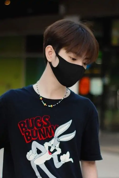 Bạn nam mặc hoodie xám đứng cạnh cửa sổ lớp học, gương mặt sáng và nụ cười nhẹ mang đúng nét học đường thân thiện