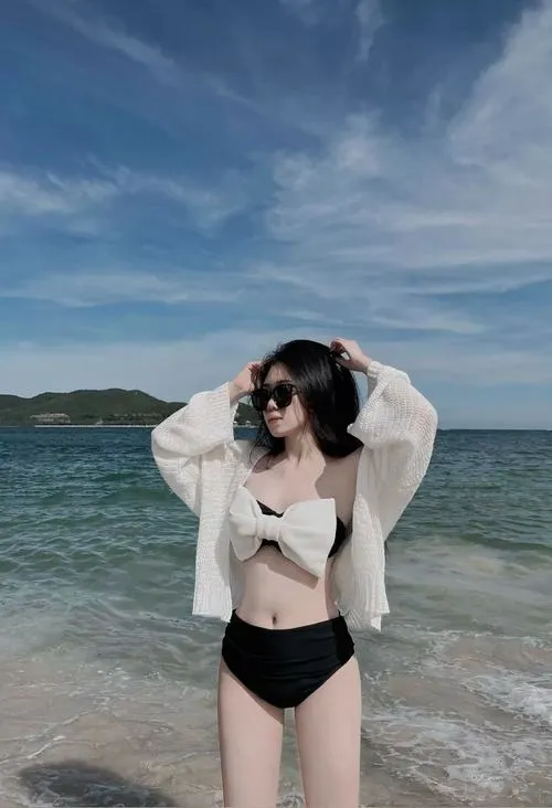 Bikini xanh nhạt hòa cùng màu nước hồ bơi, cô gái cúi nhẹ bên thành bể với tóc ướt và dáng người mảnh mai