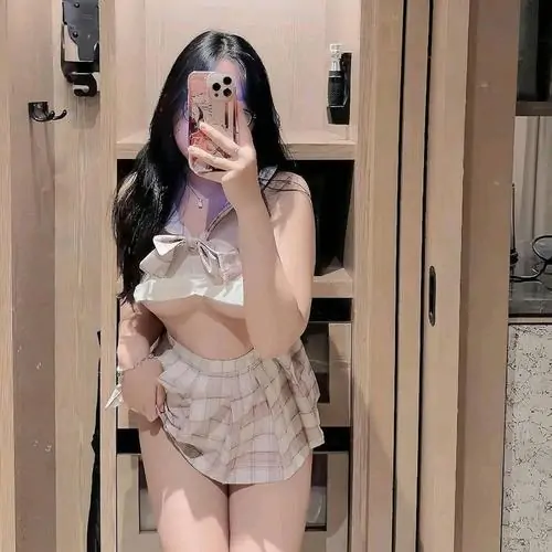 Trước gương phòng ngủ, cô gái diện váy hai dây trắng phối quần ren, tóc dài buông xuống vai tạo nét nữ tính