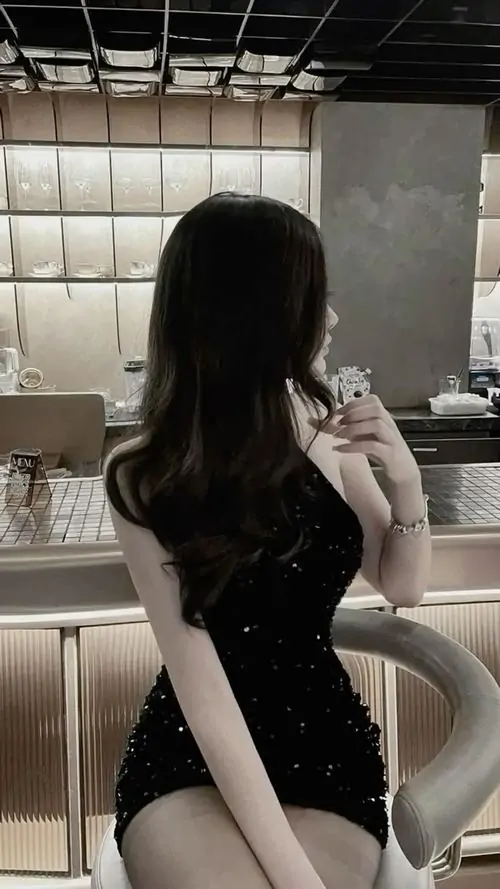 Dáng lưng cô nàng trong hình nền cô gái mặc đầm đen ôm sát nổi bật giữa thang máy, tóc dài và bờ vai gọn
