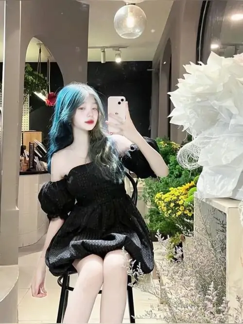 Ánh đèn trong nhà làm nổi bật cô nàng diện váy đen hai dây, mái tóc xanh khói và dáng ngồi tự tin giữa không gian sang