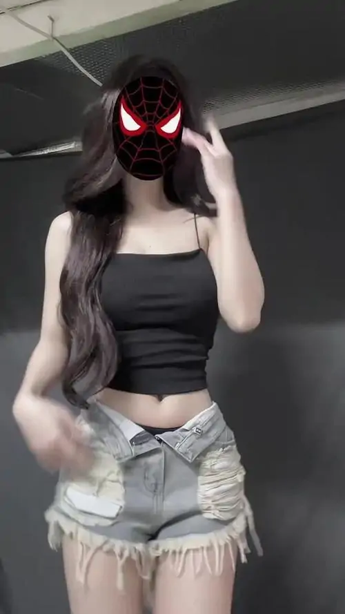 Áo hai dây đen ôm dáng cùng quần short sáng màu làm cô gái nổi bật khi tạo dáng nhảy trước gương, tóc dài buông mềm che vai