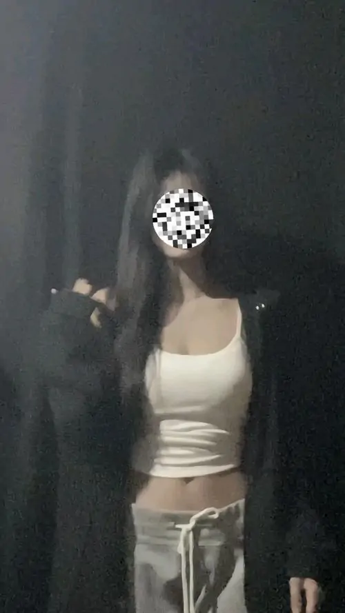 Trước nền tối, hình gái xinh vũ đạo ghi lại cô gái mặc áo trắng ngắn, quần rộng sáng màu và dáng đứng khá tự tin