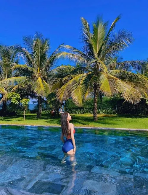 Dưới hàng dừa và nền trời xanh rực, hình ảnh Hương Giang mặc bikini ghi lại khoảnh khắc quay lưng thả dáng bên hồ bơi mát lành