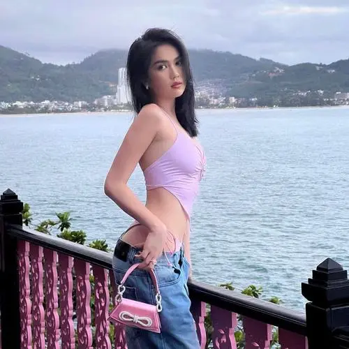 Bikini tím nhạt bên ban công nhìn ra biển tạo cảm giác dịu mắt, dáng đứng nghiêng và mái tóc dài làm khung hình mềm hơn