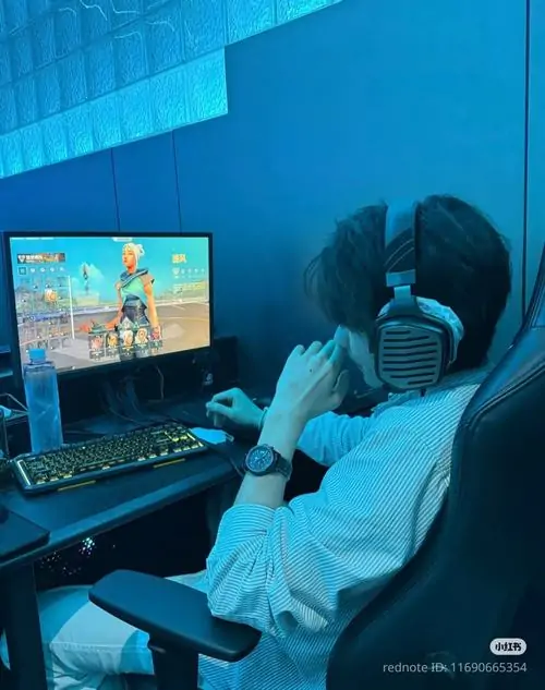 Ánh sáng xanh lam từ màn hình máy tính phản chiếu lên góc nghiêng của chàng trai đeo tai nghe chụp tai đang ngồi chơi game ban đêm.