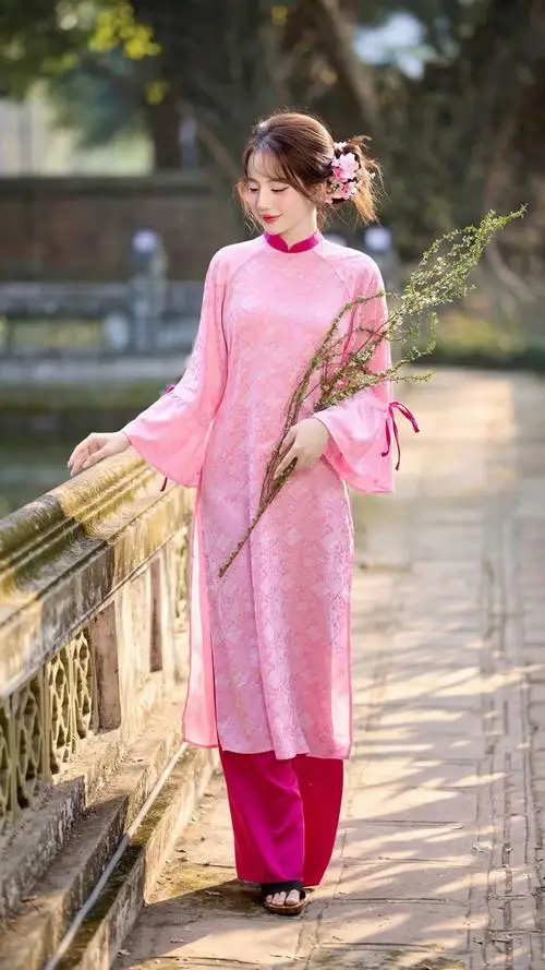 Tà áo hồng nổi bật giữa lối đi rợp nắng, cô gái bước chậm bên lan can với tư thế chụp hình áo dài mềm mại