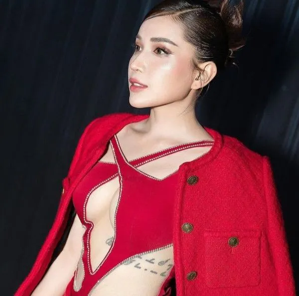 Áo khoác đỏ với đường cắt táo bạo tạo điểm nhấn cho hình bikini Khả Như, tóc búi cao và ánh mắt nghiêng đầy tự tin